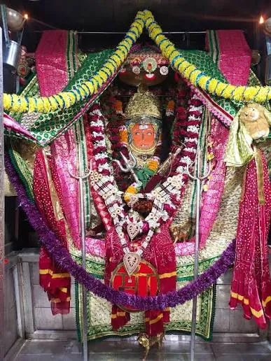 Jeen Mata adorned with a green and pink chunari, trishul and garlands of marigold